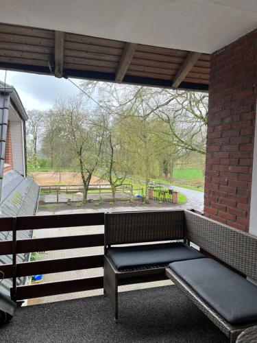 a bench sitting in a porch with a brick wall at Wunderschöne Ferienwohnung mit Balkon auf dem Bauernhof in Greven
