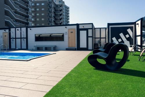 a large black object sitting on the grass next to a pool at HUBHUB Shin-yurigaoka in Shiomidai