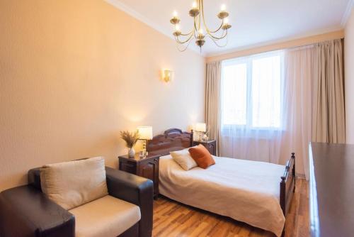 a bedroom with a bed and a chair and a window at GG Home - 1-Bedroom apartment in Saburtalo near metro in Tbilisi City