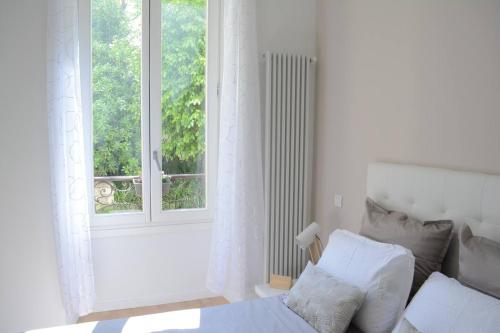 une chambre blanche avec un lit et une fenêtre dans l'établissement Appartement Cosy et Plage, à Nice