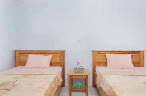 two beds in a room with a nightstand between them at Coco Divers & Homestay Bunaken in Manado