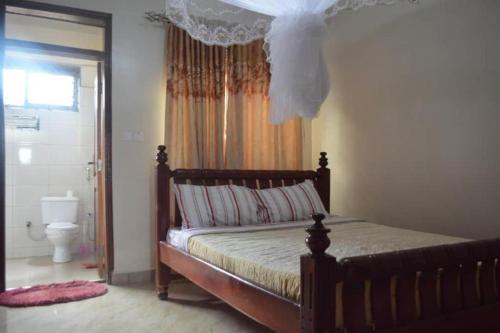 a bedroom with a bed with a canopy and a toilet at Serene Homes in Jinja