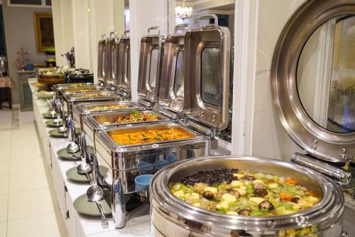 a row of buffet dishes of food in metal pans at At Pingnakorn Nimman Hotel in Chiang Mai