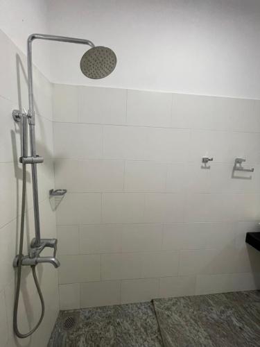 a shower in a bathroom with white tiles at Hotel Eco Garden in Buttala