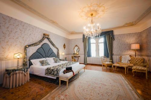 a bedroom with a large bed and a chandelier at Castello Di Spessa - Residenze d'epoca in Capriva del Friuli