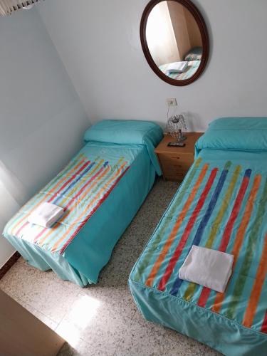 a bedroom with two twin beds and a mirror at Pensión Glorioso Hostel in Picaraña