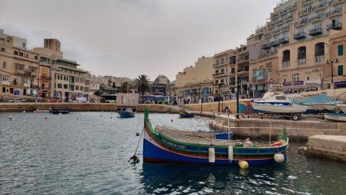 a boat in the water in a city with buildings at Malta Crown guesthouse in St Julian's