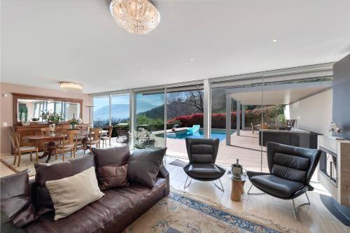 ein Wohnzimmer mit einem braunen Ledersofa und Stühlen in der Unterkunft Villa Dolce Vita With Private Pool - Happy Rentals in Lugano