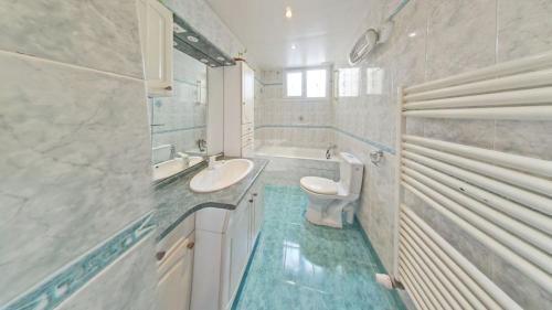bagno bianco con lavandino e servizi igienici di le blanc mesnil a Le Blanc-Mesnil