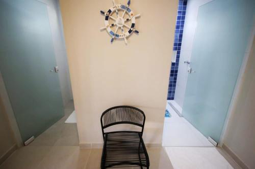 a black chair in a room with a clock on the wall at Parada IT in Japaratinga