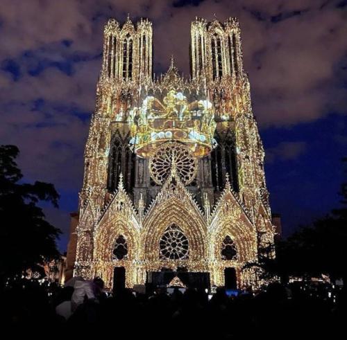 une grande cathédrale éclairée la nuit avec des lumières dans l'établissement IXO’s The Suite, à Reims