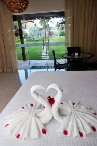 two swans made out of towels on a bed at Parada IT in Japaratinga