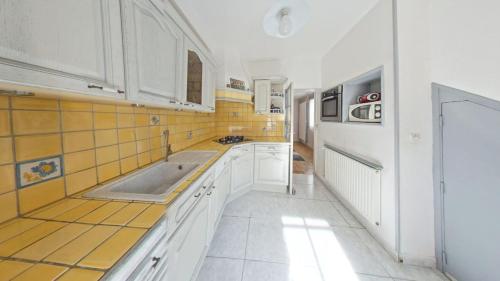 a kitchen with white cabinets and yellow tiles on the wall at le blanc mesnil in Le Blanc-Mesnil