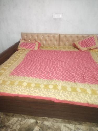 ein Bett mit einer rosa und gelben Bettdecke in der Unterkunft VEDIK GRAM in Begusarai