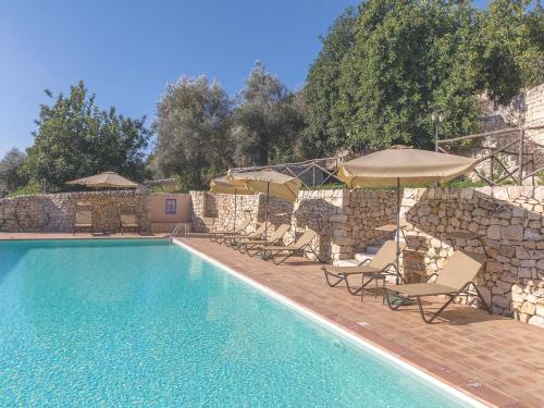 a swimming pool with chairs and umbrellas next to a building at Baglio Fasana in Modica