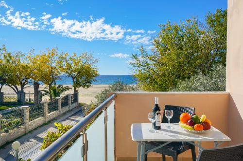 a balcony with a table with a bowl of fruit and wine glasses at Lampiris Beach Front Apartments in Potos