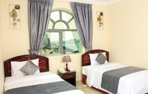 a hotel room with two beds and a window at Al BARAKAH HOTEL in Sharjah