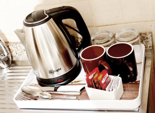 a tea kettle and coffee cups on a kitchen counter at Al BARAKAH HOTEL in Sharjah
