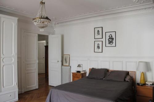 une chambre avec un lit et un lustre dans l'établissement 5 bdr, 10 ppl Georgous Typical Parisian Flat, à Paris