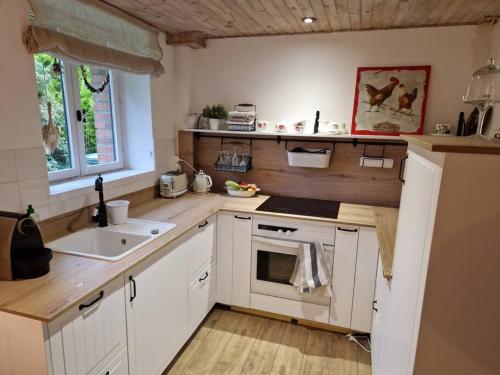 une cuisine avec des armoires blanches et un évier dans l'établissement Petit cottage breton, à Saint-Mayeux