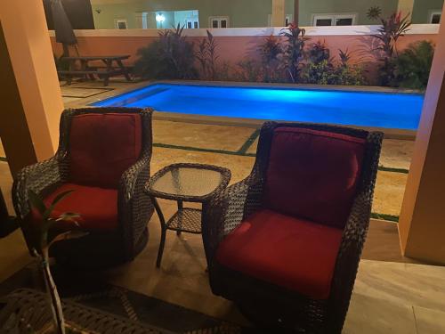 twee stoelen en een tafel en een zwembad bij Island Breeze Guest Suite in Nassau