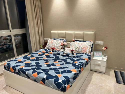 a bedroom with a bed with a blue and orange comforter at 1BHK In Hiranandani Powai (D) in Mumbai