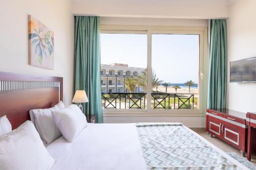a bedroom with a large bed and a large window at Oyster Bay Beach Suites in Abu Dabbab