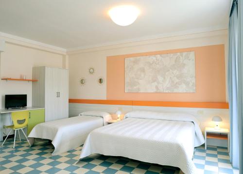 two beds in a room with orange walls and checkered floors at Hotel The Marquee in Castelnuovo di Garfagnana