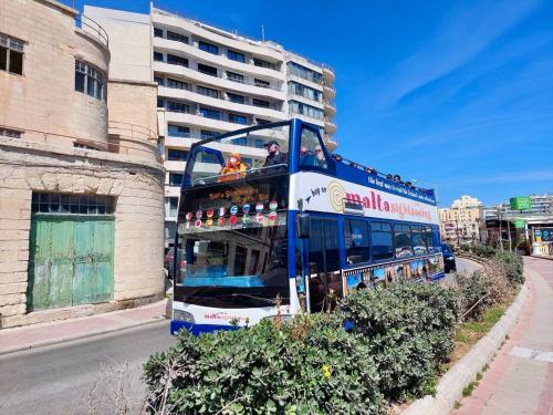 a double decker bus driving down a city street at Malta Crown guesthouse in St Julian's