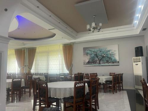 Guest-Room Zoi&Teri في Tepelenë: غرفة طعام بها طاولات وكراسي و لوحة على الحائط