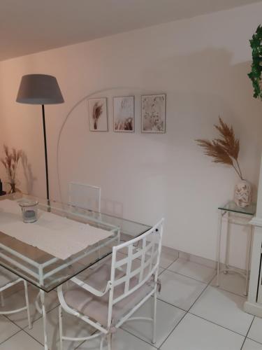 une salle à manger avec une table en verre et une chaise dans l'établissement Résidence Les Pêcheries, à Saint-Vaast-la-Hougue