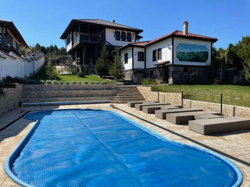 une piscine bleue en face d'une maison dans l'établissement Vila Toplika, à Kara Agach