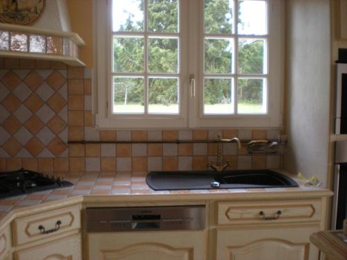 une cuisine avec un évier et deux fenêtres dans l'établissement Gites De La Grasse, à Carcassonne