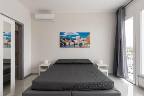 a white bedroom with a bed and a painting on the wall at Travelershome Ciampino Airport GuestHouse in Ciampino