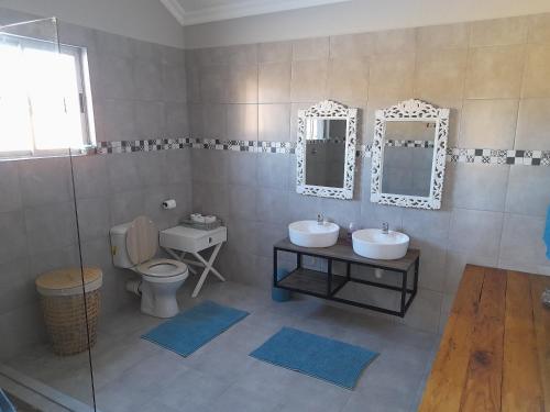 bagno con 2 lavandini, servizi igienici e specchi di Zamenkomst River Lodge a Maclear