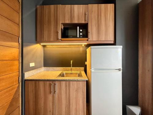 a small kitchen with a white refrigerator and a sink at Azumi Boutique Hotel in Manila