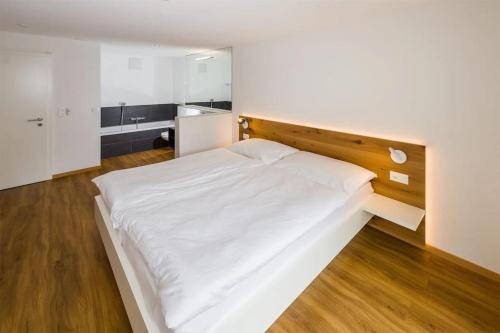 a bedroom with a large white bed with a wooden headboard at Moderne Wohnung Jungtal in Grächen