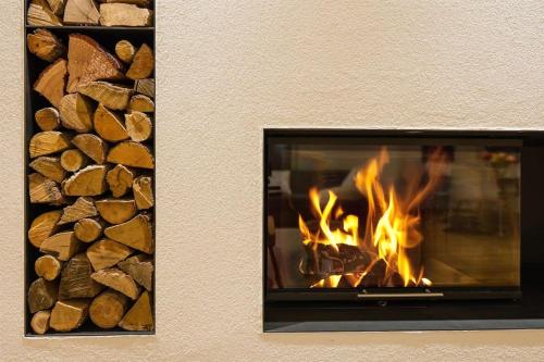 a fire in a fireplace next to a pile of logs at Moderne Wohnung Jungtal in Grächen