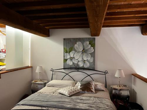 1 dormitorio con 1 cama con una pintura floral en la pared en Alloggio la fattoria, en Cecina