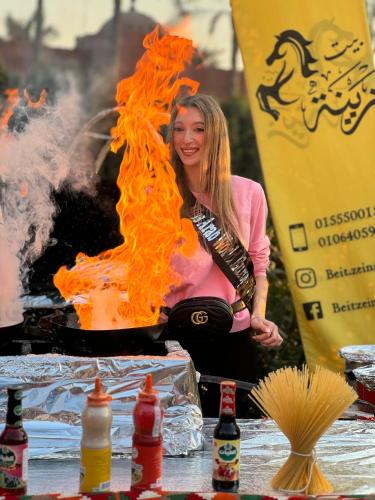 a woman is sitting in front of a fire at 2-single beds beit zeina horse riding in Cairo