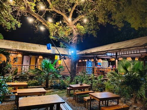 a group of picnic tables in a garden at night at Lokal Hut Bed and Breakfast in Puerto Princesa City