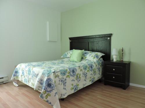 a bedroom with a bed with a wooden headboard and a table at Appartement touristique #5 Immeuble MH in LʼAnse-Saint-Jean