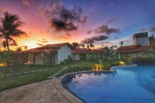 a house with a swimming pool in front of a sunset at Parada IT in Japaratinga