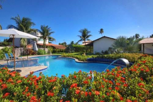 a swimming pool in a resort with flowers at Parada IT in Japaratinga