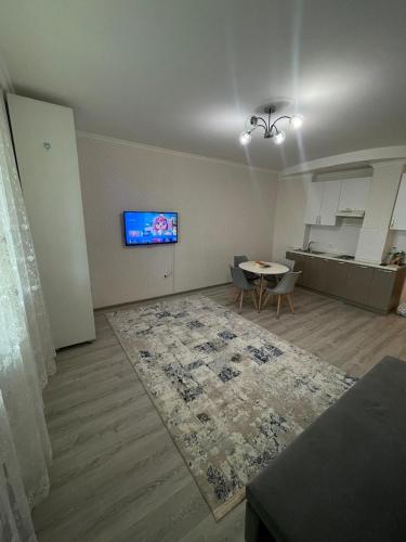 ein Wohnzimmer mit einem Tisch und einem TV an der Wand in der Unterkunft Korkem tower in Taldykolʼ