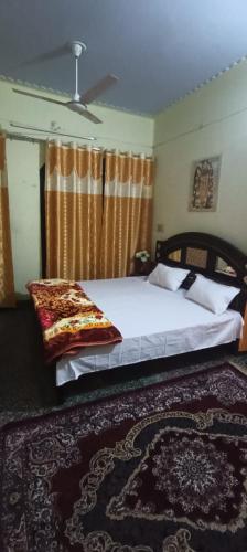 een slaapkamer met een groot bed en een tapijt bij Ratan home stay in Faizābād