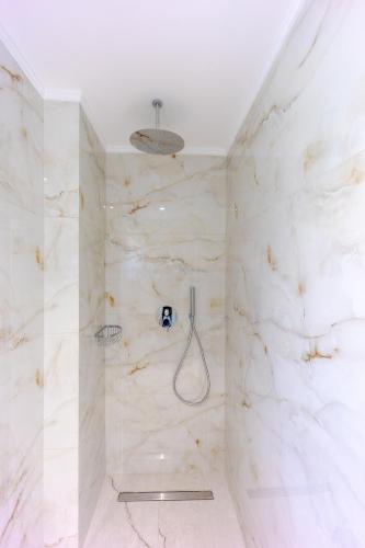 a bathroom with a shower with white marble walls at Sunny Drops Villas by Estia in Balíon