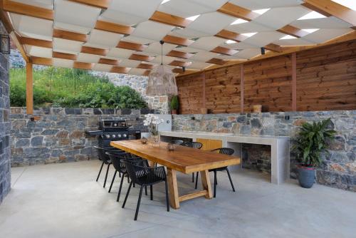 a patio with a wooden table and a fireplace at Sunny Drops Villas by Estia in Balíon