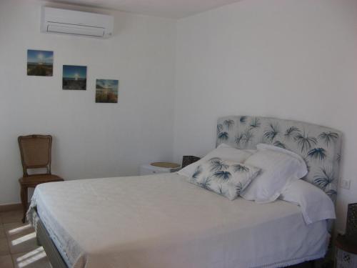 um quarto com uma cama com lençóis brancos e almofadas em Chambre d'hôtes à Usclas d'Hérault em Usclas-lʼHérault