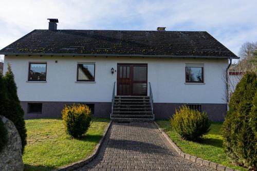 a white house with stairs leading to a door at Ferienwohnung Am Rhaunelbach in Rhaunen